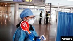 身穿防护服的工作人员在北京机场的抵达大厅检测旅客体温。(2020年3月4日)