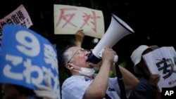 A man shouts slogans over a public-address system during a protest outside the Japanese prime minister's office, July 1, 2014.