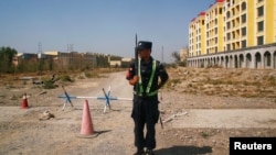 在新疆伊宁通往一个中国当局称作“职业训练中心”的再教育营的道路上,一名中国警察在站岗。(2018年9月4日)