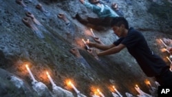 Một người Tây Tạng lưu vong đặt các ngọn nến trên tác phẩm điêu khắc 'Bức tường của Người Tây Tạng Tử Đạo' trong đêm đốt nến cầu nguyện ở Dharamsala, Ấn Độ để tỏ tình đoàn kết với những người Tây Tạng tự thiêu