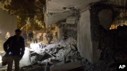 这张利比亚政府组织的参访时拍摄的照片显示,官员和媒体记者在查看被北约导弹攻击后的受损的房子。