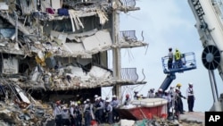 在佛罗里达州迈阿密郊区的瑟夫赛德,工作人员在倒塌后的尚普兰塔大厦南公寓楼的废墟上进行搜救工作。(2021年6月28日)