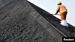 资料照：一名中国工人在山东日照港铲着从澳大利亚进口的煤炭。（资料照片）