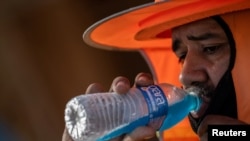 2023年7月28日,亚利桑那州斯科茨代尔,一名建筑工人在连续27天温度超过110华氏度的热浪中喝冷饮。