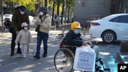 北京一家儿童医院外一名坐在轮椅上的男孩手拿医院影像科的片子。(2023年11月24日)