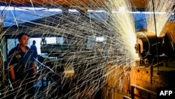 中国山东省青州市一个汽车轮辋工厂的工人正在生产线上工作。(2024年6月17日)