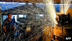 中国山东省青州市一个汽车轮辋工厂的工人正在生产线上工作。(2024年6月17日)