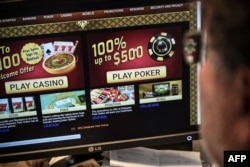 Seorang jurnalis AFP memperhatikan situs judi online di Washington DC, 17 Januari 2019. (Foto: Eric Baradat/AFP/ilustrasi)