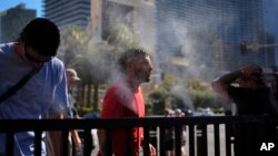 资料照片:人们在拉斯维加斯街道上的喷雾器中乘凉。(2024年7月7日)