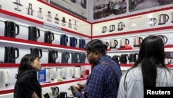 资料照:广州举办的广交会上一个家用小电器生产商举办人员与参观者交谈。(2023年4月16日)