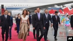 在新华社发布的这张照片中,叙利亚总统巴沙尔·阿萨德(中右)和第一夫人阿斯玛·阿萨德于2023年9月21日抵达中国杭州。