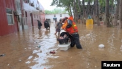 中国救援人员在房山县救助疏散受到洪水袭击的一名幼童。(2023年7月31日)