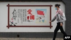 一名女子走过北京街头的一面中国政府宣传社会主义核心价值观的宣传墙。(2021年6月9日)