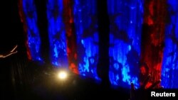 Seorang peneliti mendemonstrasikan instalasi yang terdiri dari tekstil cerdas yang berubah warna sebagai respons terhadap gerakan tangan dan gerak tubuh di Hong Kong, China, 5 Juni 2023. (REUTERS/Joyce Zhou)