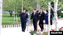 Pemimpin Korea Utara Kim Jong Un berjalan bersama Presiden China Xi Jinping selama kunjungan Xi di Pyongyang, Korea Utara, dalam foto yang dirilis oleh Kantor Berita Pusat Korea Utara (KCNA) 21 Juni 2019. (KCNA via REUTERS)