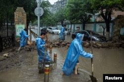 北京居民开始清理被洪水淹没的街道。(2023年8月1日)