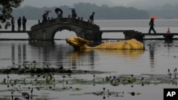 中国杭州第十九届亚运会期间,游客们穿过广受欢迎的西湖风景区金色公牛雕塑旁的石桥