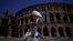 Seorang turis tampak melindungi wajahnya dari sinar matahari dengan kipas yang ia bawa saat berkunjung ke Colosseum di tengah gelombang panas yang menyerang Roma, pada 11 Juli 2023. (Foto: Reuters/Guglielmo Mangiapne)