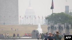 游客在被烟雾笼罩的首都华盛顿游玩。(2023年6月7日)