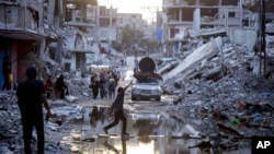 资料照片:巴勒斯坦人在加沙南部汗尤尼斯的街头废墟中行走。(2024年7月4日)