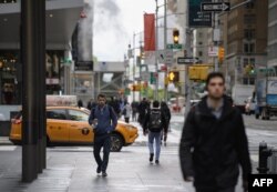 Para pejalan kaki di pusat kota Manhattan, New York City, 10 Mei 2021. Kawasan bisnis New York kembali ramai, dengan antrean saat makan siang di bar yang menjual salad, setelah perusahaan-perusahaan besar memanggil karyawannya untuk kembali bekerja dari kantor mereka yang terletak di gedung-gedung pencakar langit kota tersebut. (Angela Weiss / AFP)