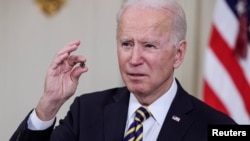 资料照:拜登总统在白宫签署有关解决全球半导体芯片短缺的行政令期间手拿芯片发表讲话。(2021年2月24日)