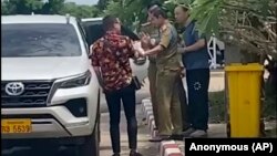 在这张由一位不愿透露姓名的消息人士拍摄的影片中,两名活动人士中的一位(左)与中国维权律师卢思位(右)同行,与拘留卢思位的警察发生争执,2023 年7月28 日 (匿名消息来源向美联社提供照片)