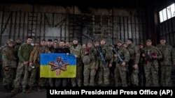 乌克兰总统泽连斯基(中)前往俄乌正在激战的巴赫穆特附近的一处阵地与乌军士兵举着军旗合影。(2023年3月22日)