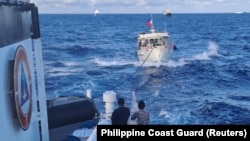 一艘菲律宾‘海岸警卫队船只拖着一艘遭中国海岸警卫队水炮攻击毁坏了的菲律宾供应船驶向有争议的第二托马斯岛礁(中国称为仁爱礁)。(2023年12月10日)