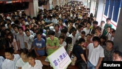 资料照:中国河南省郑州的一个招聘会上众多年轻人等在富士康招聘办公室的门前接受面试。(2010年8月11日)