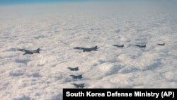 韩国国防部发布照片显示美日韩战机在三方联合军演中飞越韩国济州岛上空。(2023年12月20日)