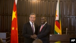 资料照:2020年1月12日,中国外交部长王毅(左)在津巴布韦哈拉雷与津巴布韦外交部长西布西索·莫约举行联合新闻发布会握手。