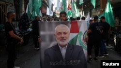 在黎巴嫩贝鲁特的一个巴勒斯坦难民营,人们举着哈马斯领导人伊斯梅尔·哈尼亚 (Ismail Haniyeh) 的画像游行抗议他被刺杀。(2024年7月31日)