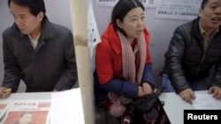 资料照片: 2016年2月23日招聘人员在中国北京招聘会上与求职者交谈