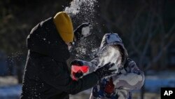 2023年12月17日,一女子在北京一座居民楼附近跟一孩子玩雪。北京在过去两个星期经历了几十年未见的低温天气。