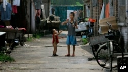 资料照:两个农民工的孩子在北京郊区一个破旧的农民工住宅区里玩耍。(2008年8月12日)