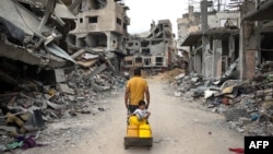 一名巴勒斯坦男子在加沙地带南部汗尤尼斯满是废墟的街道上拉着一辆手推车。(2024年5月2日)