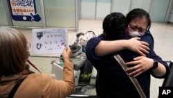 资料照片:2023年3月14日,北京首都国际机场一名女子等到了乘坐国际航班抵达北京的亲人。(美联社照片)