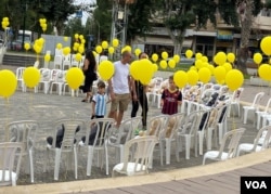 特拉维夫北边的拉马特哈沙隆(Ramat Hasharon)的市政府大楼旁的圆环广场有市民自发设置、摆放近200多张白色空椅、各张椅子上贴有被绑人质照片的小海报、幼童人质的椅子上还置放了泰迪熊等毛绒玩具,表达人们对人质及人质家人的支持和关注。(美国之音/赖素芬)
