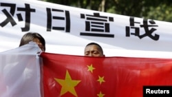 资料照:抗议者在日本驻北京的大使馆外举横幅纪念日本二战战败67周年(2012年8月15日)