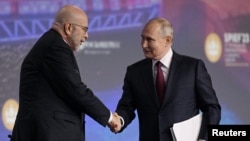 资料照片:俄罗斯总统弗拉基米尔·普京在圣彼得堡国际经济论坛的一次会议期间与主持人德米特里·西姆斯握手。(2023年6月16日)