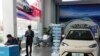 Tim marketing dari produsen mobil listrik BYD berdiri di dekat mobil listrik pabrikan tersebut di sebuah showroom di Beijing, pada 10 April 2024. (Foto: AP/Ng Han Guan)