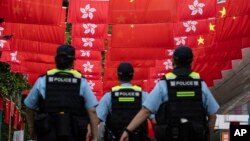香港警察在香港主权移交中国27年纪念日走过挂满中国国旗和香港旗帜的街道。(2024年7月1日)