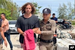 Seorang petugas polisi Thailand mengawal Daniel Sancho Bronchalo dari Spanyol atas dugaan pembunuhan dan pemotongan seorang ahli bedah Kolombia dari pulau Koh Phagnan ke pengadilan Pulau Koh Samui, Thailand selatan, Senin, 7 Agustus 2023. (AP Photo/Somkeat Ruksaman)