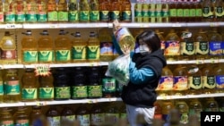 资料照:中国辽宁省沈阳市一家超市里,一名顾客在购买食用油。(2022年10月9日)