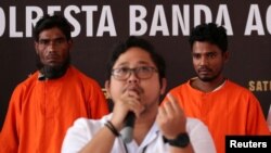 Seorang warga negara Bangladesh dan seorang Rohingya yang dicurigai menyelundupkan setidaknya 400 pengungsi Rohingya, berdiri di belakang Fadillah Aditiya Pratama dalam konferensi pers di kantor polisi di Banda Aceh, 27 Desember 2023. (Antara Foto/Irwansyah Putra/via REUTERS)