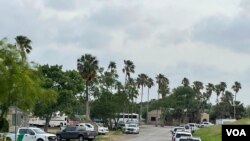 移民渡河上岸后到达美国布朗斯维尔的这个地方，然后被送到移民受理中心拘押。路边停着边境执法人员的车辆。远处蓝色帐篷是给移民做初步登记的地方。