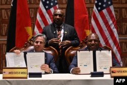 Menteri Luar Negeri AS Antony Blinken (kiri) dan Menteri Pertahanan Papua Nugini Win Bakri Daki (kanan) menunjukkan dokumen setelah penandatangan pakta keamanan disaksikan oleh Perdana Menteri Papua Nugini James Marape (tengah) pada Forum untuk India -Kerja Sama Kepulauan Pasifik di APEC Haus di Port Moresby, 22 Mei 2023. (ADEK BERRY/AFP)