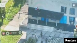 2024年8月14日发布在社交媒体的视频截图显示,在俄乌冲突中乌克兰军人在俄罗斯库尔斯克地区的一座建筑物上扯下一面俄罗斯国旗。