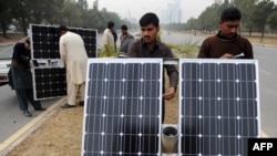 资料照片:2014年2月2日巴基斯坦工人在伊斯兰堡的道路分隔线上准备太阳能灯板。